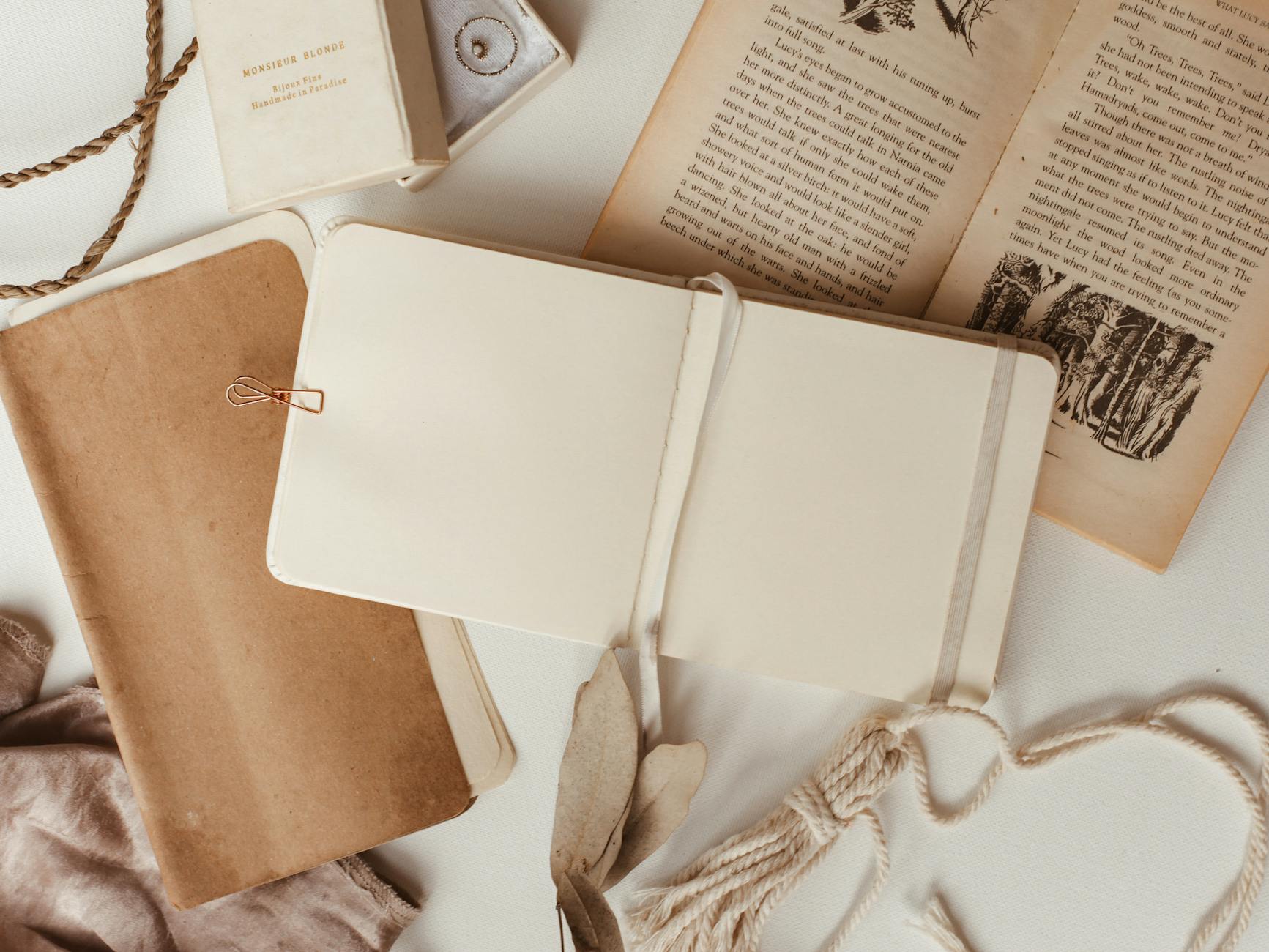 Раскрытый блокнот с винтажной книгой на бежевой поверхности
